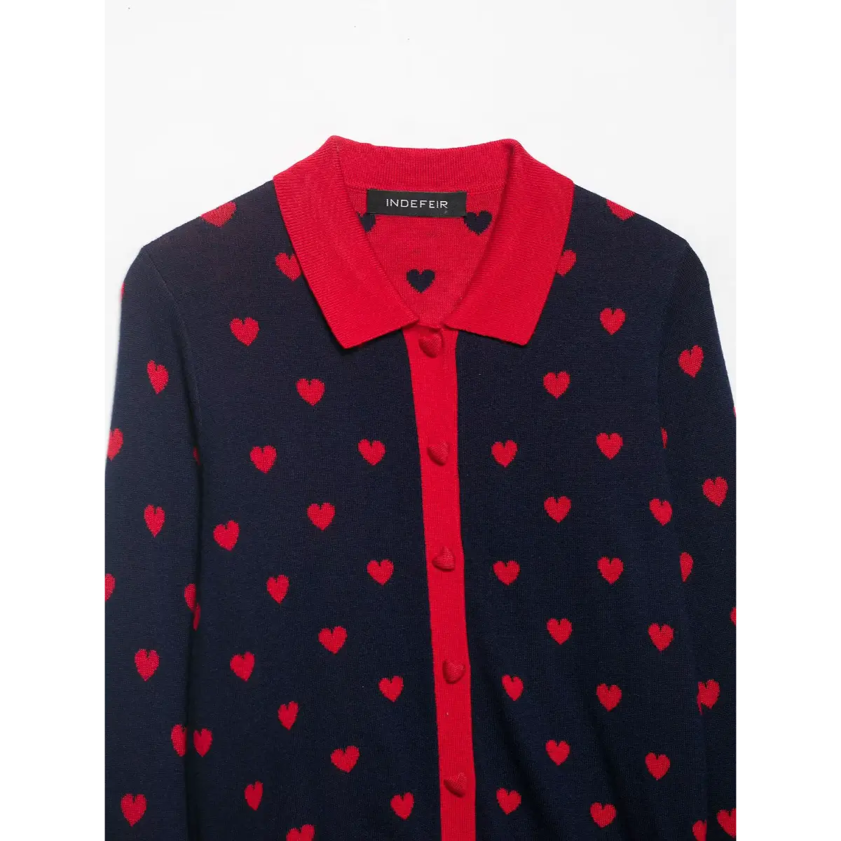  Studio shot of a navy and red heart-patterned knit cardigan with red trim, heart-shaped buttons, and cropped length