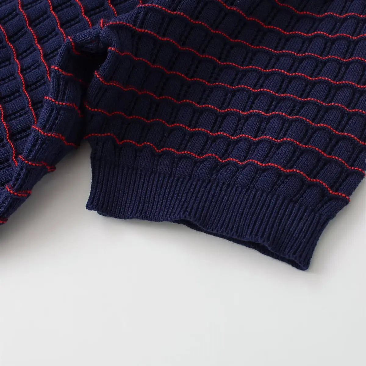 Sleeve cuff detail of navy and red striped knit cardigan, showing the ribbed finish and openwork pattern