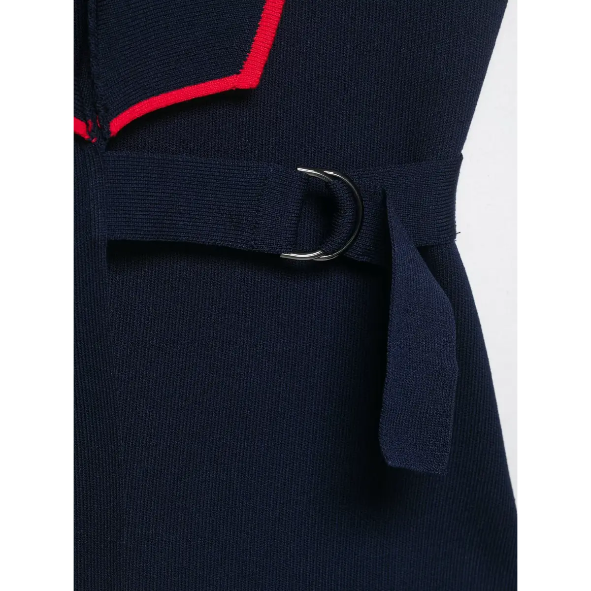 Close-up of the side belt buckle detail on the navy knit vest with red piping