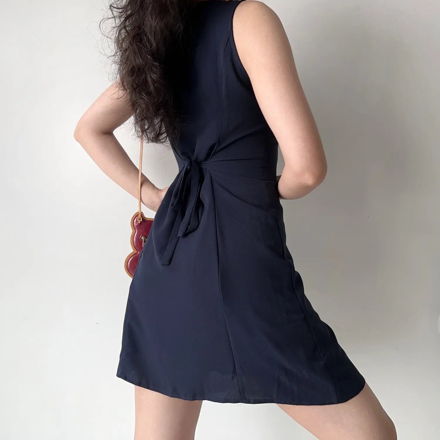 Model back view navy sleeveless notched collar mini dress self tie waist back detail a‑line short dress