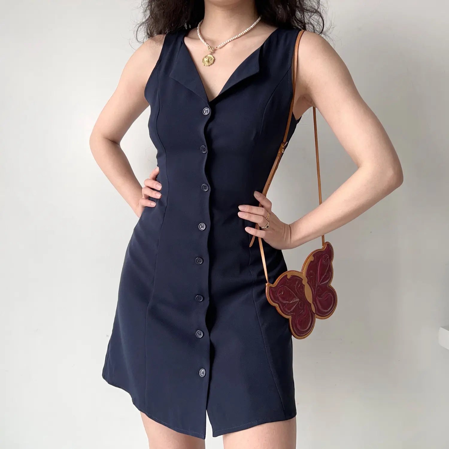 Model hands on hips pose navy sleeveless notched collar button‑front mini dress office casual short dress