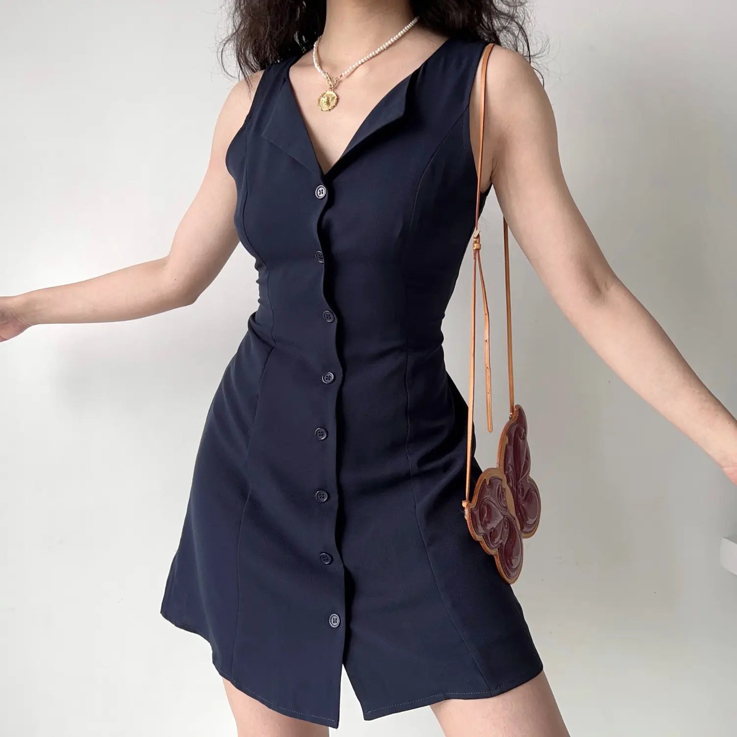 Model front spread arms pose navy sleeveless notched collar mini dress full front button down short dress