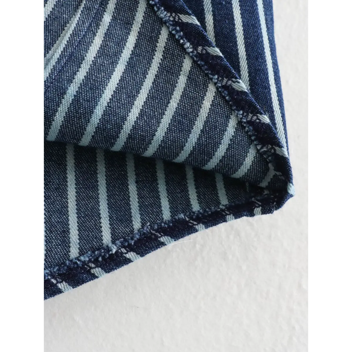 Close-up of the vest's fabric showing the blue and white stripes and finished hem.