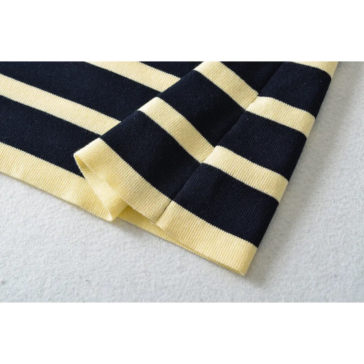 Close-up detail of the finished hem on a navy and pale yellow striped ribbed knit maxi dress.