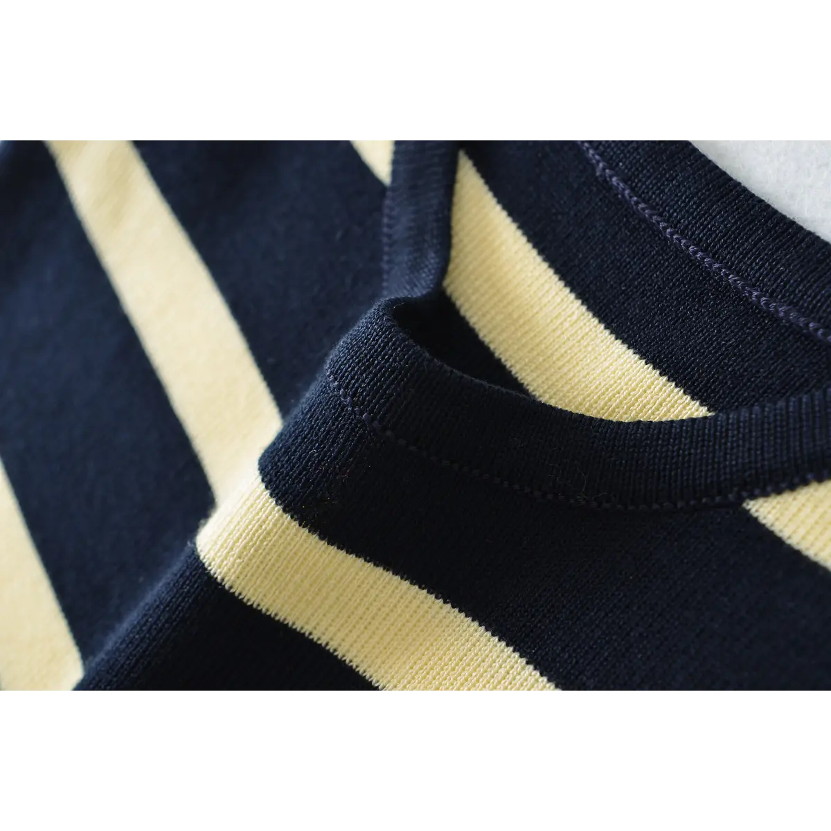 Close-up detail of the finished scoop neckline on a navy and pale yellow striped ribbed knit maxi dress, showing the clean stitching and fabric texture.
