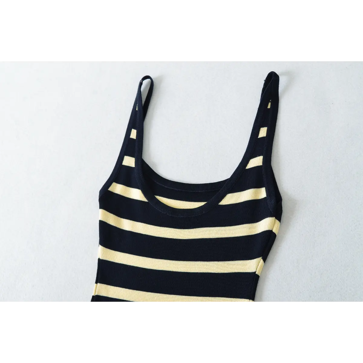  Close-up detail of the scoop neckline and straps on a navy and pale yellow striped ribbed knit maxi dress.