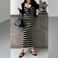 A woman wearing a navy and pale yellow striped ribbed knit maxi dress with a black cardigan, styled with accessories.
