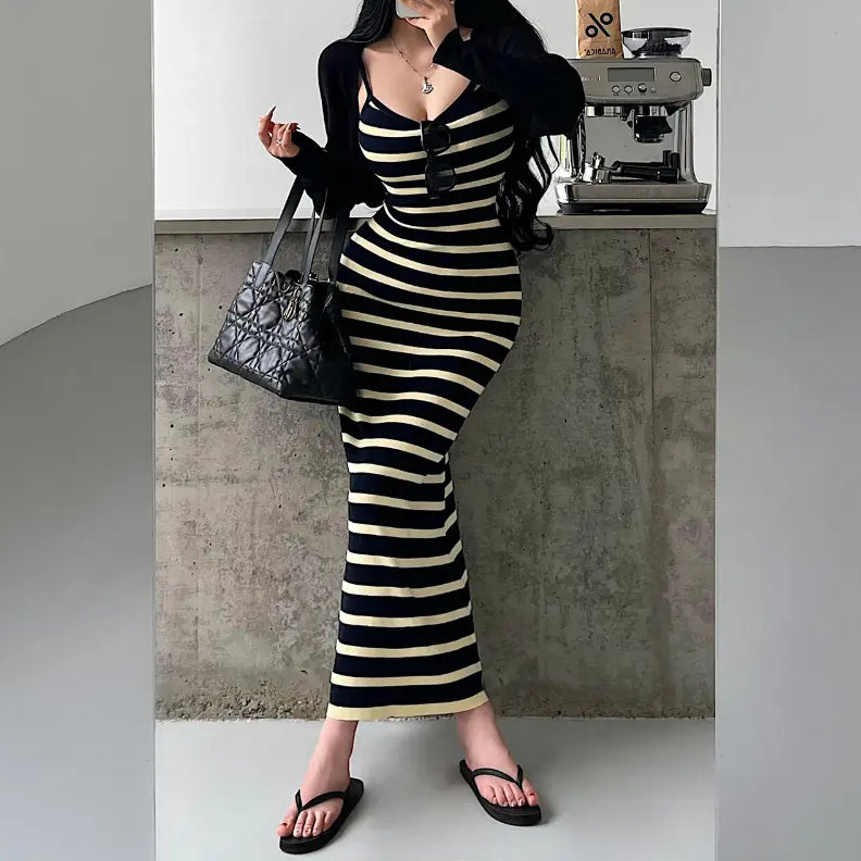 A woman wearing a navy and pale yellow striped ribbed knit maxi dress with a black cardigan, styled with accessories.
