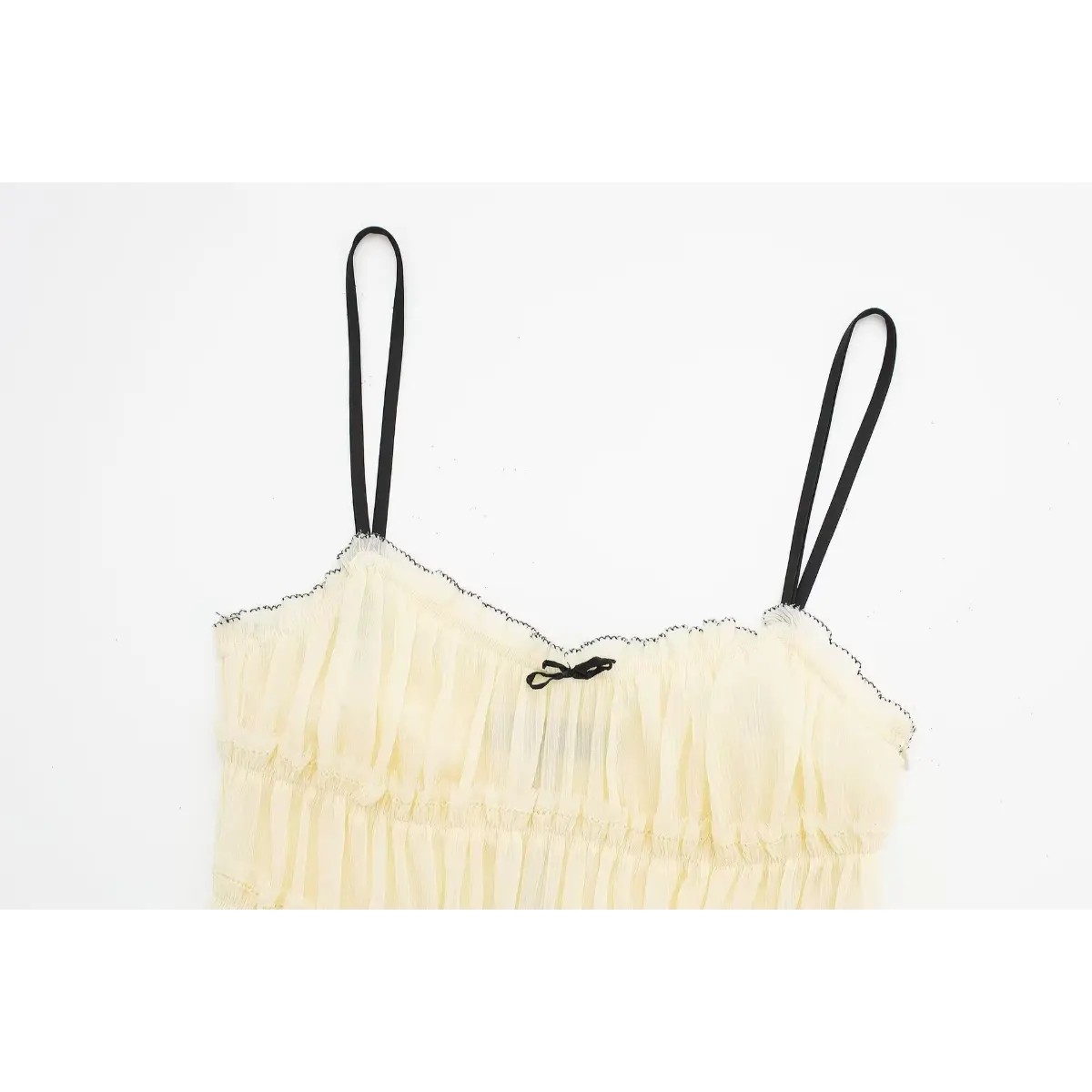 Top-down view of the front neckline on a cream smocked cami dress, showing the contrast stitching, bow detail, and spaghetti straps.