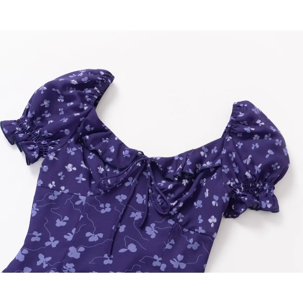 Close-up of the sweetheart neckline and puff sleeves on a purple floral print dress, showing the ruffled trim and elasticated cuffs.