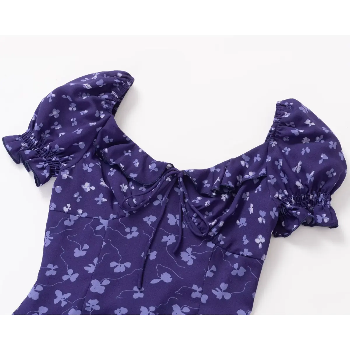 Close-up of the front tie detail on a purple floral print dress, focusing on the ruffled sweetheart neckline and gathered bust.