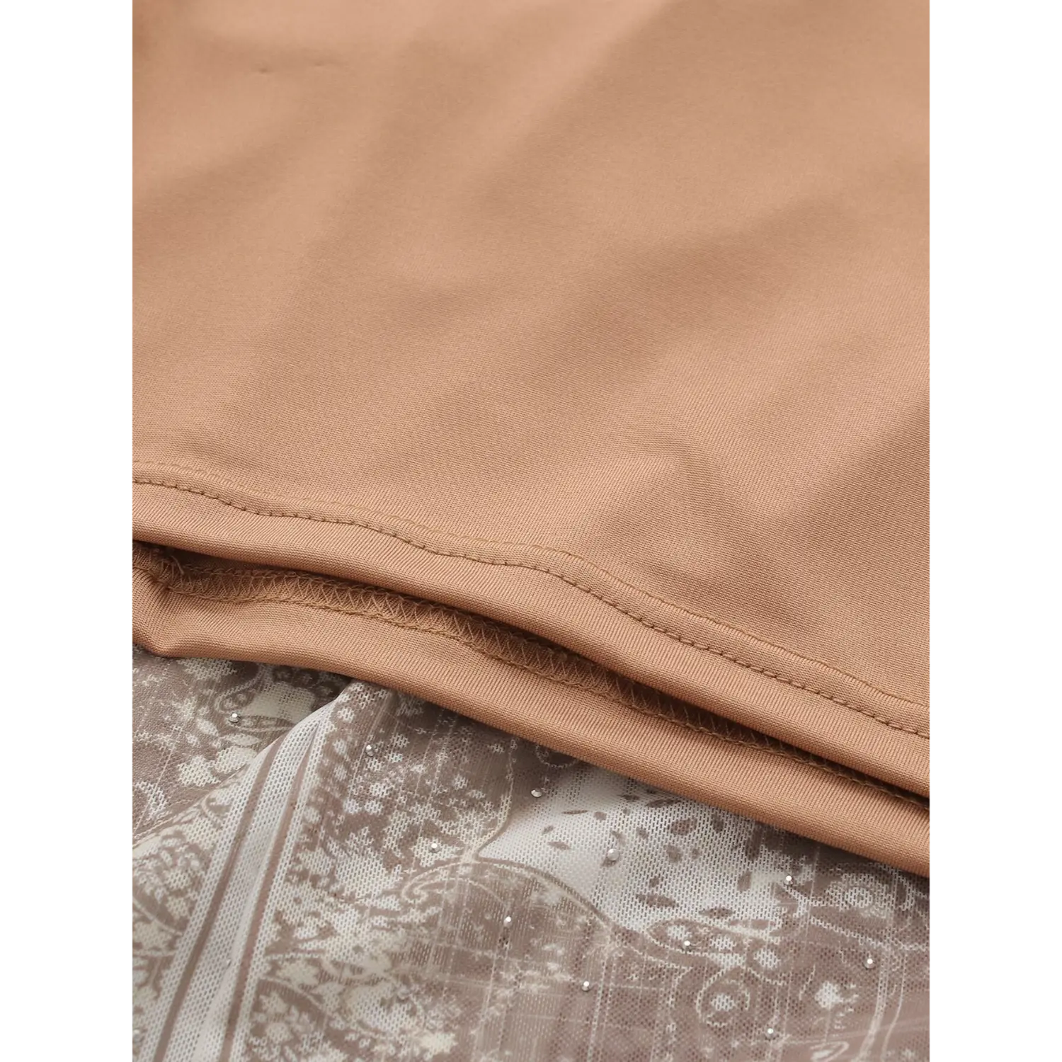Close-up hem stitching shot, solid stretch nude full lining with neat double overlock serged seams, overlay sheer stretch mesh outer fabric with vintage brown bandana paisley print and scattered tiny silver hotfix rhinestones