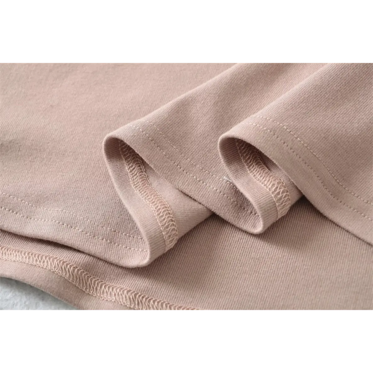 Close-up detail of the finished hem and fabric texture on a nude halter-neck mermaid maxi dress.