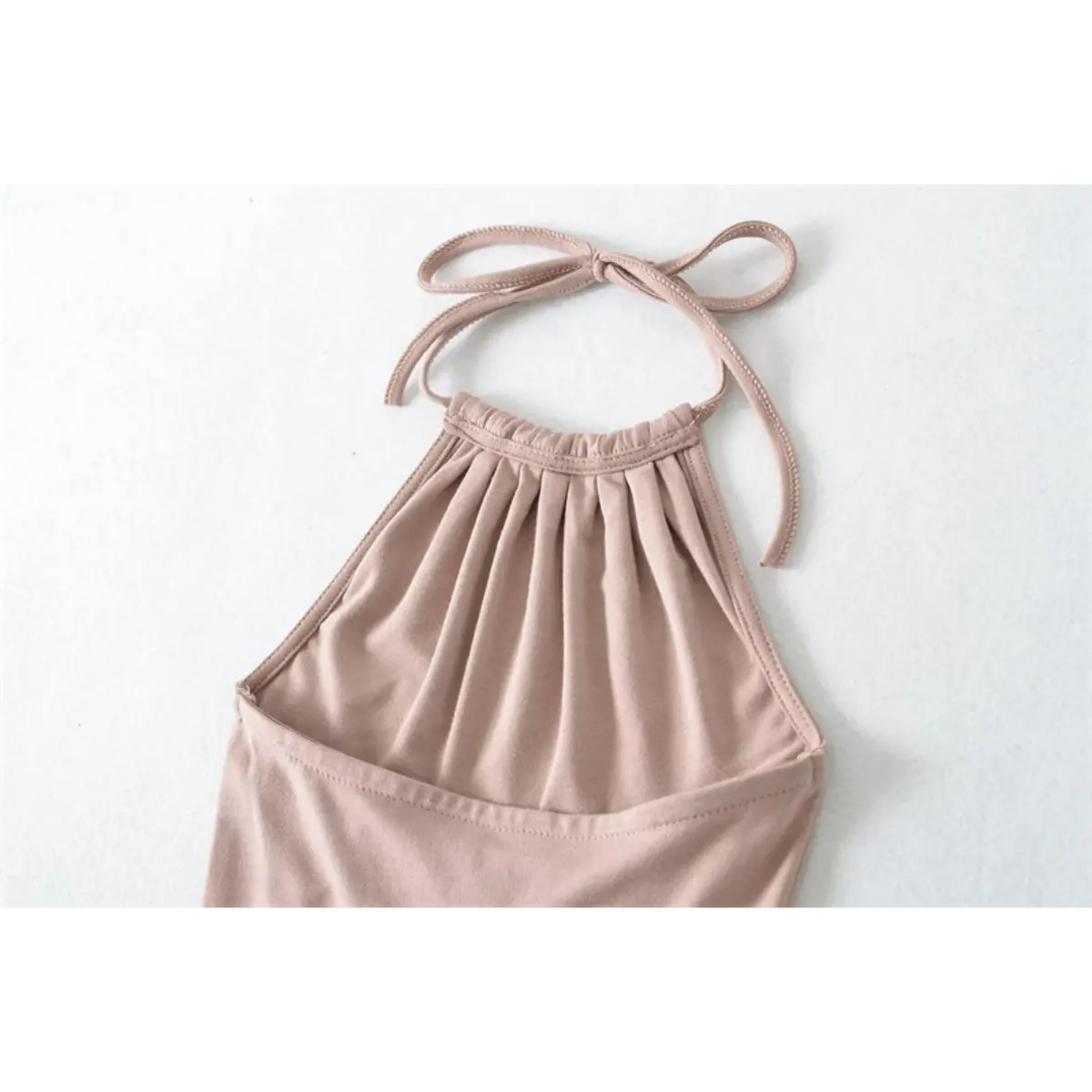 Close-up detail of the halter neckline on a nude mermaid maxi dress, showing the gathered elastic top and tied bow straps.