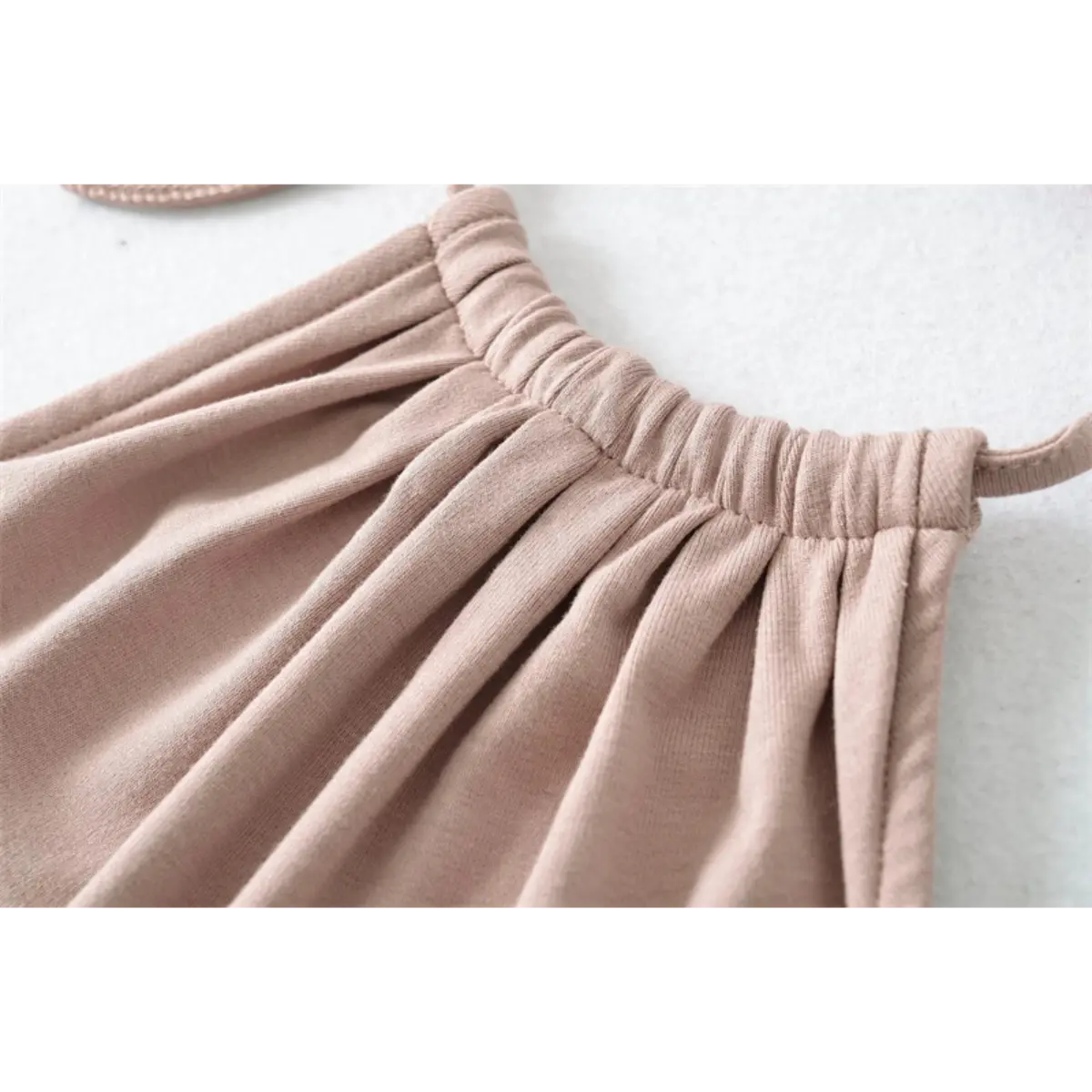 Close-up detail of the gathered and elasticated halter neckline on a nude mermaid maxi dress.