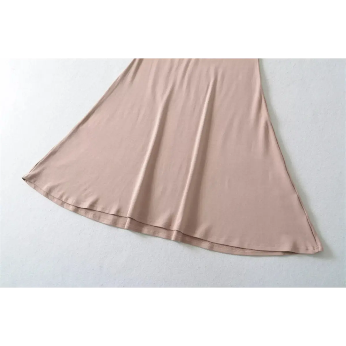 Close-up detail of the mermaid skirt on a nude halter-neck maxi dress, showing the fabric drape and finished hem.