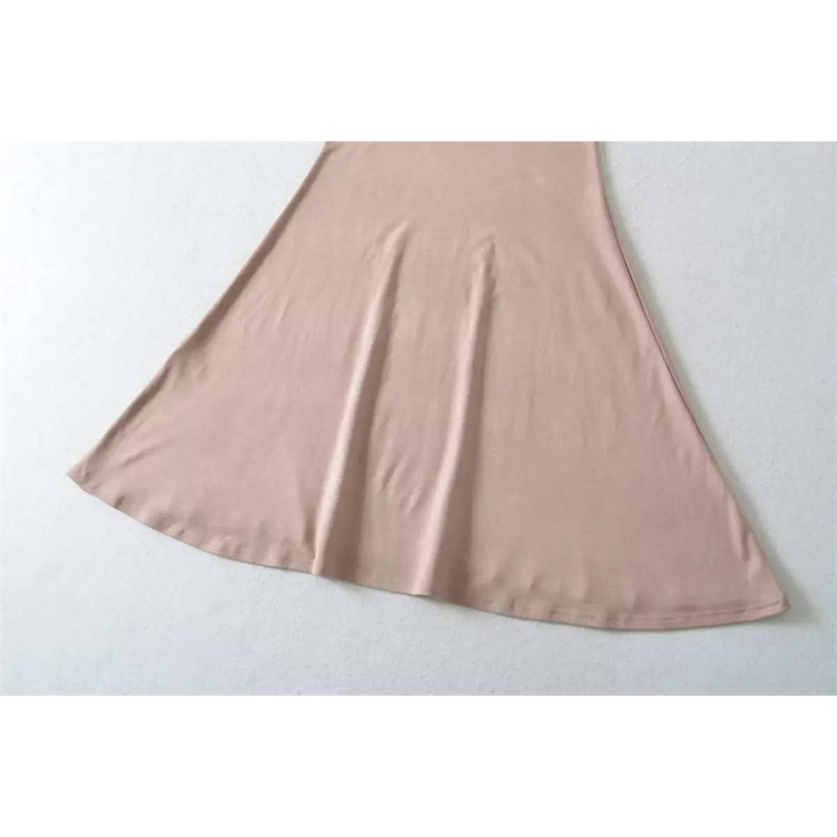 Close-up detail of the mermaid skirt hem on a nude halter-neck maxi dress, showing the finished edge and fabric drape.
