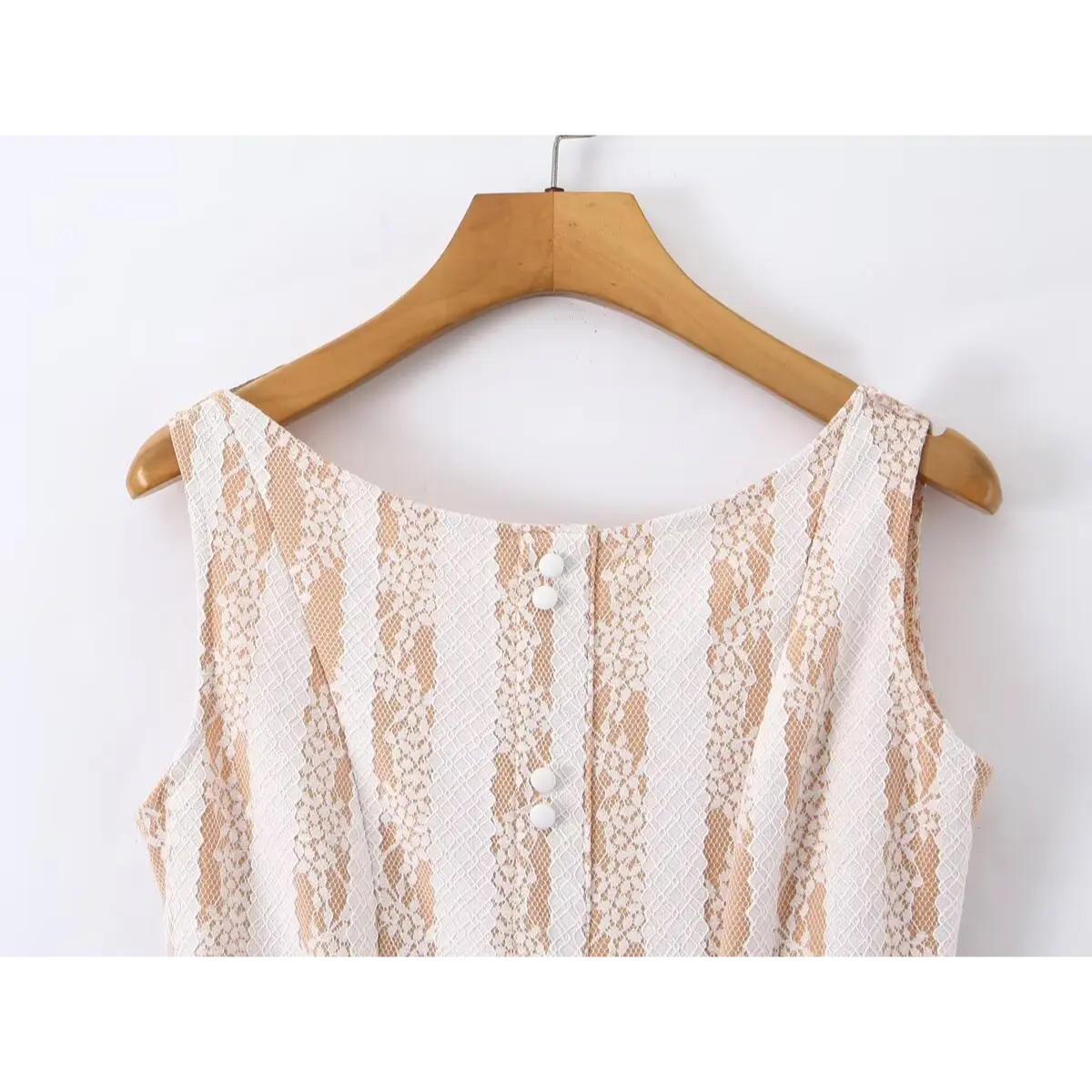 Close-up shot of the white decorative buttons on the front of a nude lace striped mini dress, highlighting the lace pattern and stitching.