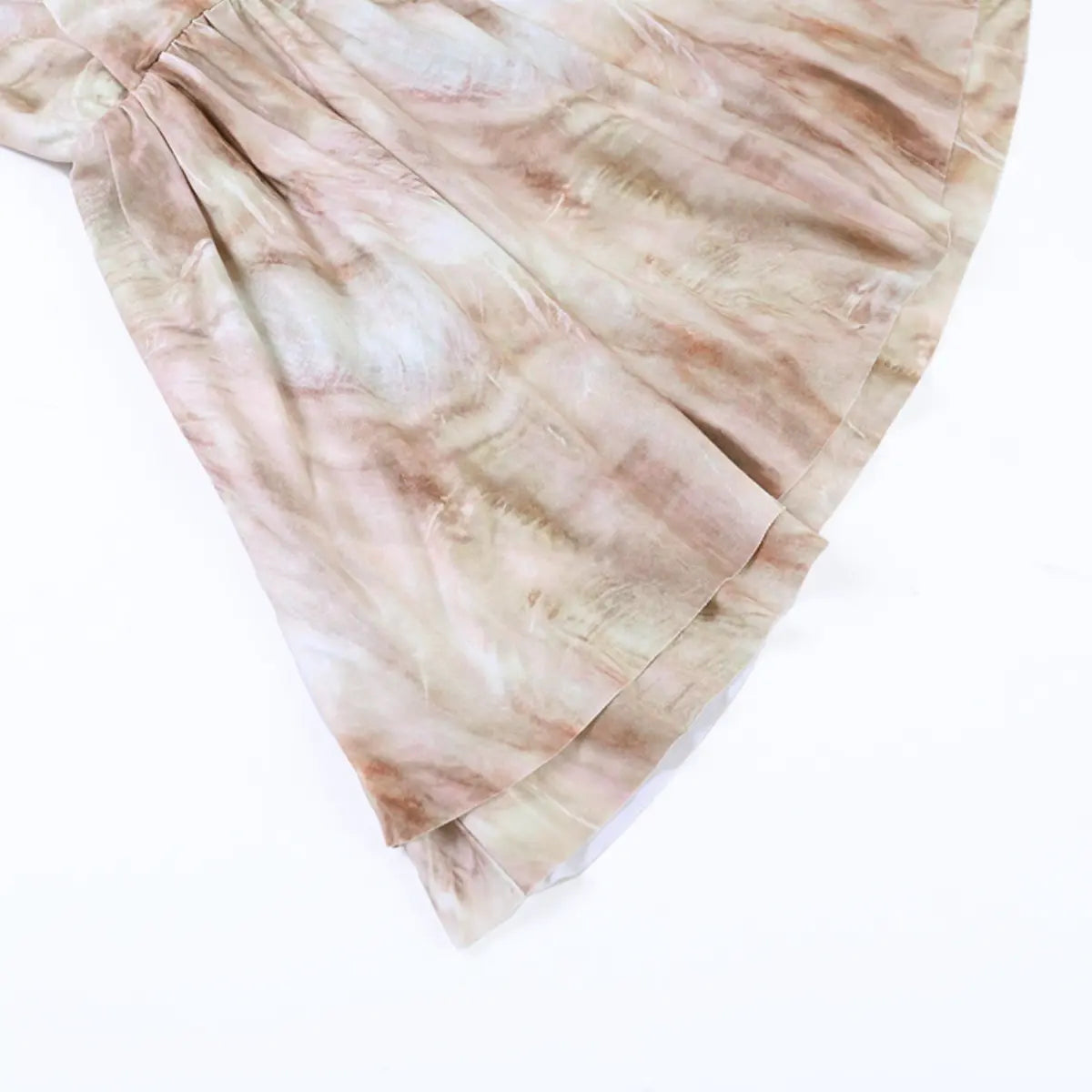 Hem detail of the nude tie-dye tiered dress, showing the double-layered skirt and soft fabric texture