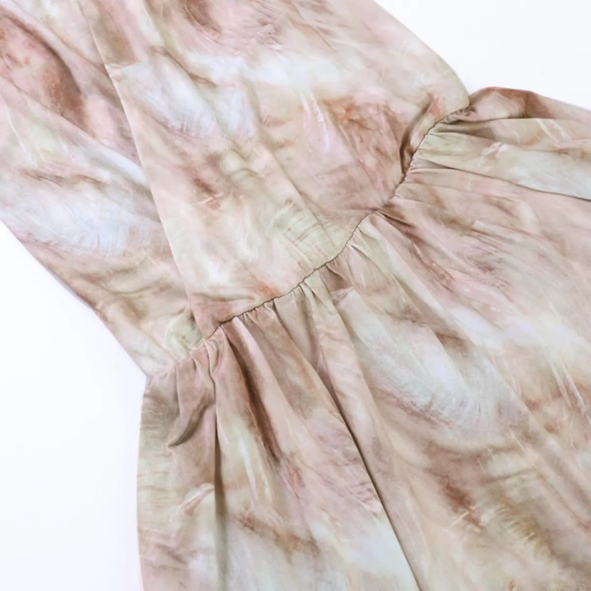 Tier detail of the nude tie-dye dress, showing the gathered waist seam and flowy skirt layers