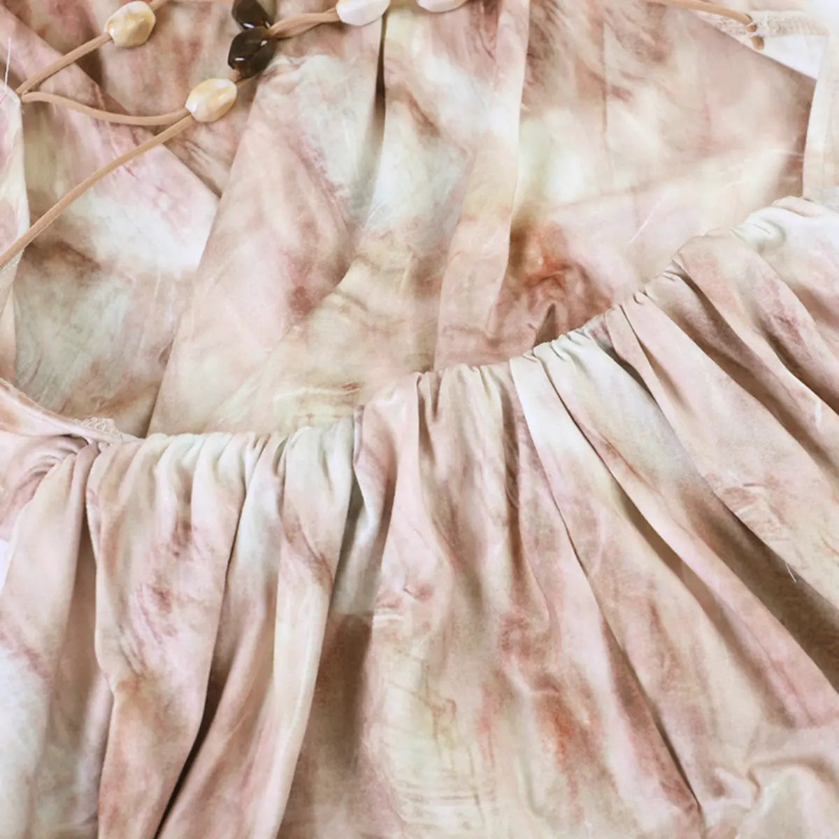 Waist detail of the nude tie-dye dress, showing the gathered tier and soft fabric