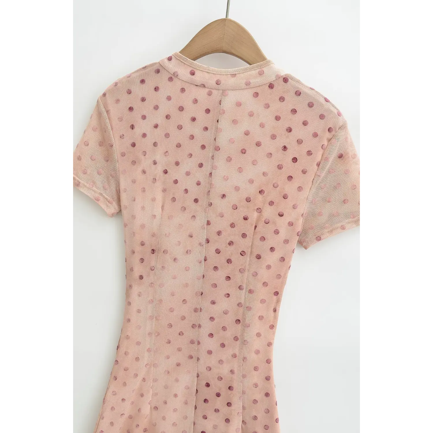 Back bodice view of nude pink polka dot maxi dress hanging on wooden hanger