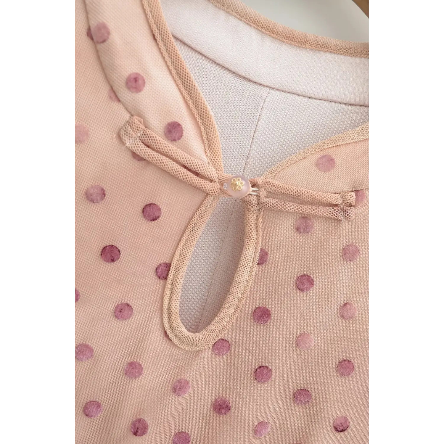 Close‑up of keyhole knot neck detail on nude pink polka dot cheongsam maxi dress