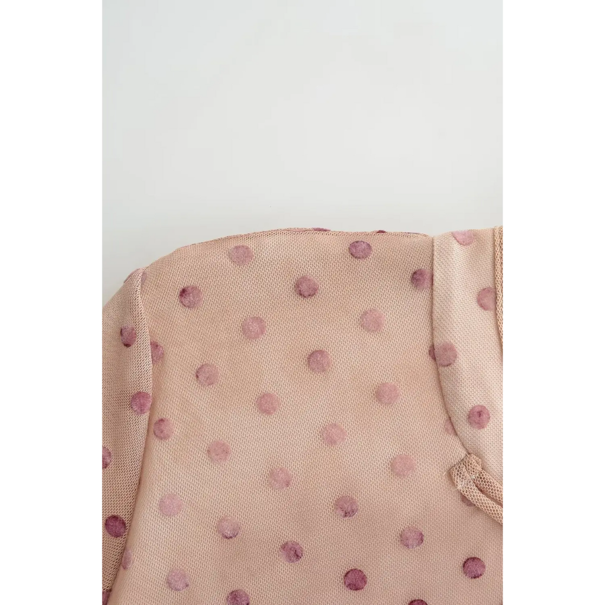Macro close‑up of nude pink fabric with dark polka dot print