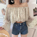 Close-up view of the off-shoulder cream blouse with black dot print, showing the elasticated neckline and flowy sleeves