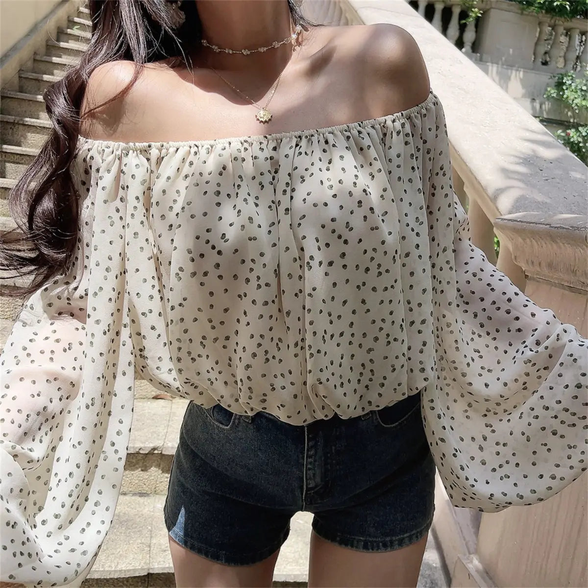 Side view of the off-shoulder cream blouse with black dot print, showing the billowy sleeve silhouette and elasticated waist hem
