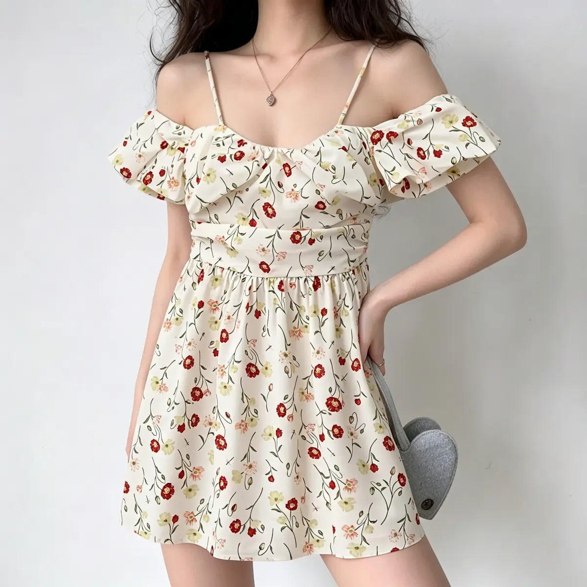 Model posing with one hand on her hip, wearing an off-shoulder floral mini dress.