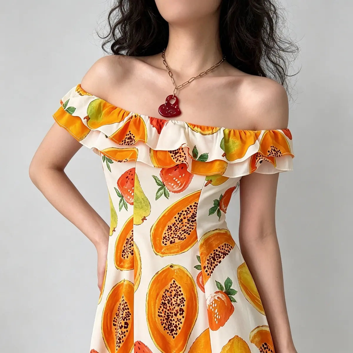  Close-up of the ruffled neckline on off-shoulder fruit print dress, showing vibrant papaya and strawberry pattern.
