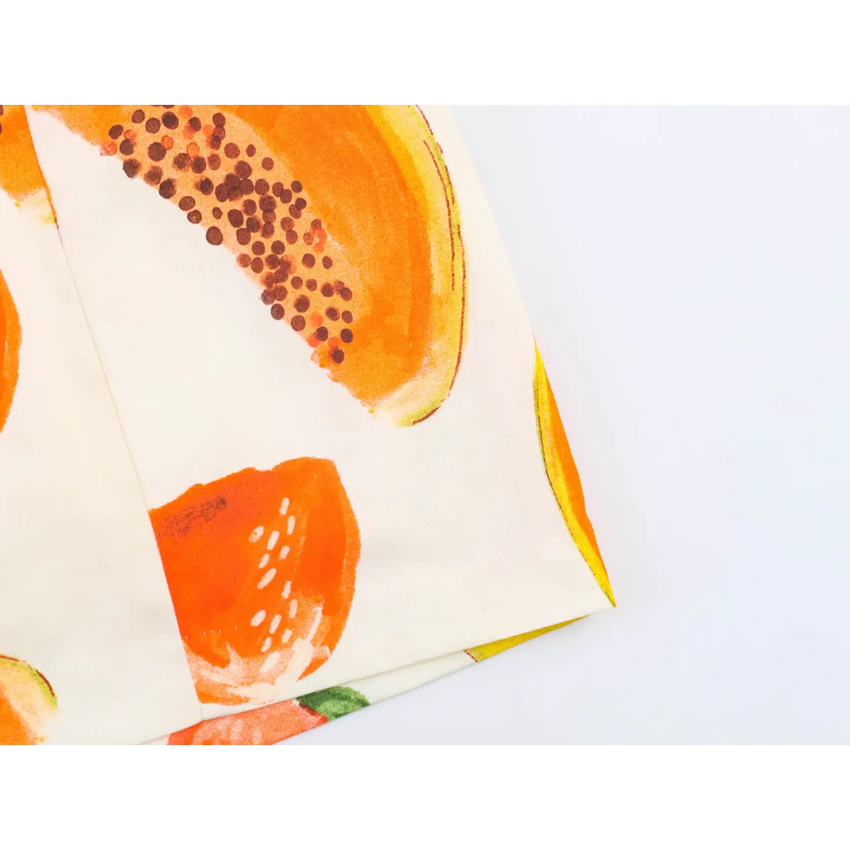 Close-up of the fruit print fabric on off-shoulder dress, showing watercolor-style papaya and strawberry print.