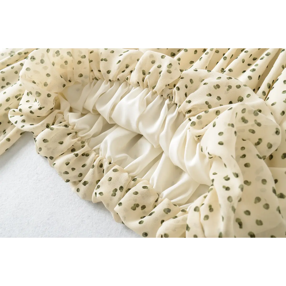 Close-up of the gathered waist on the off-shoulder cream blouse with green polka dots, showing the elasticated hem and inner lining
