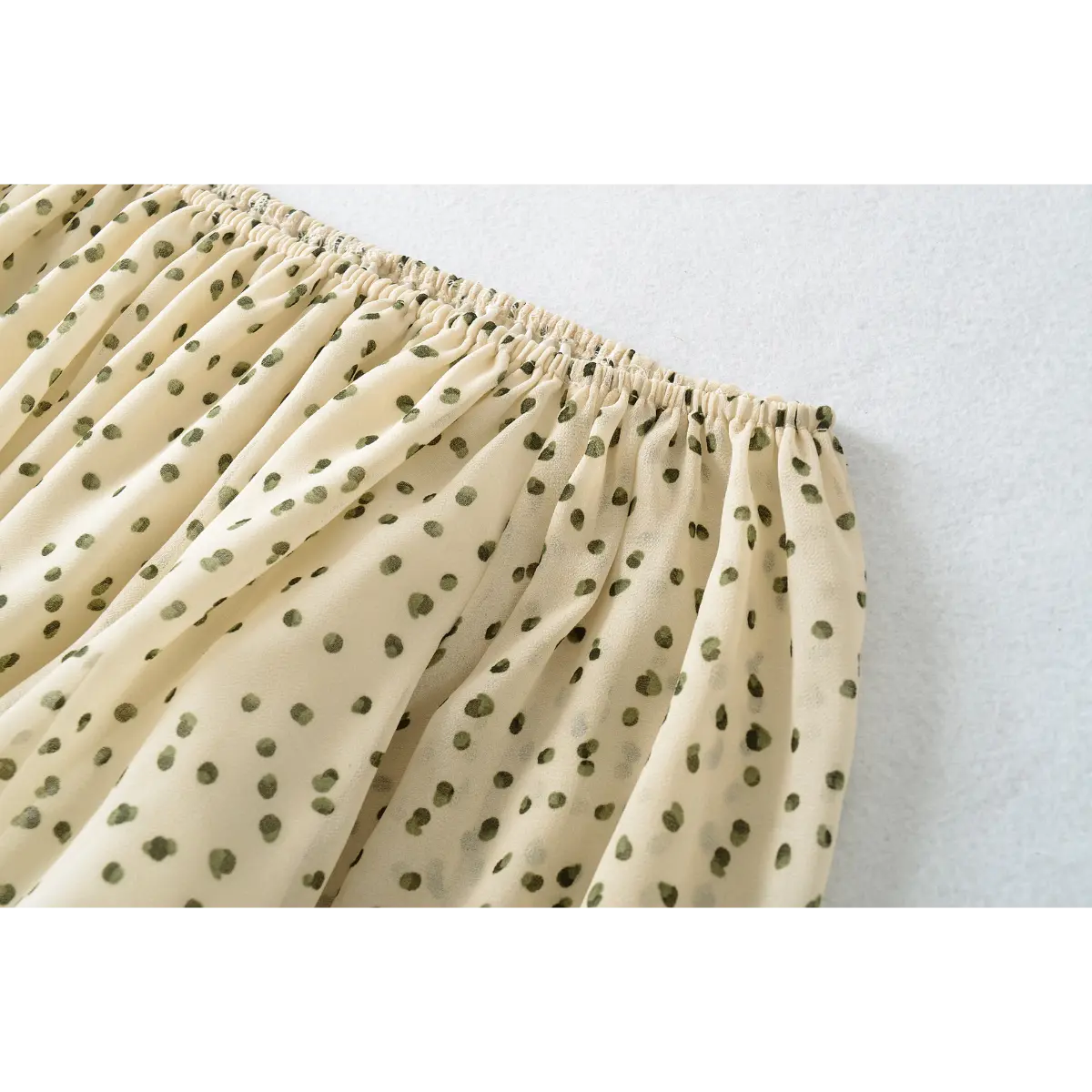 Close-up of the top elastic on the off-shoulder cream blouse with green polka dots, showing the stretch and fabric drape