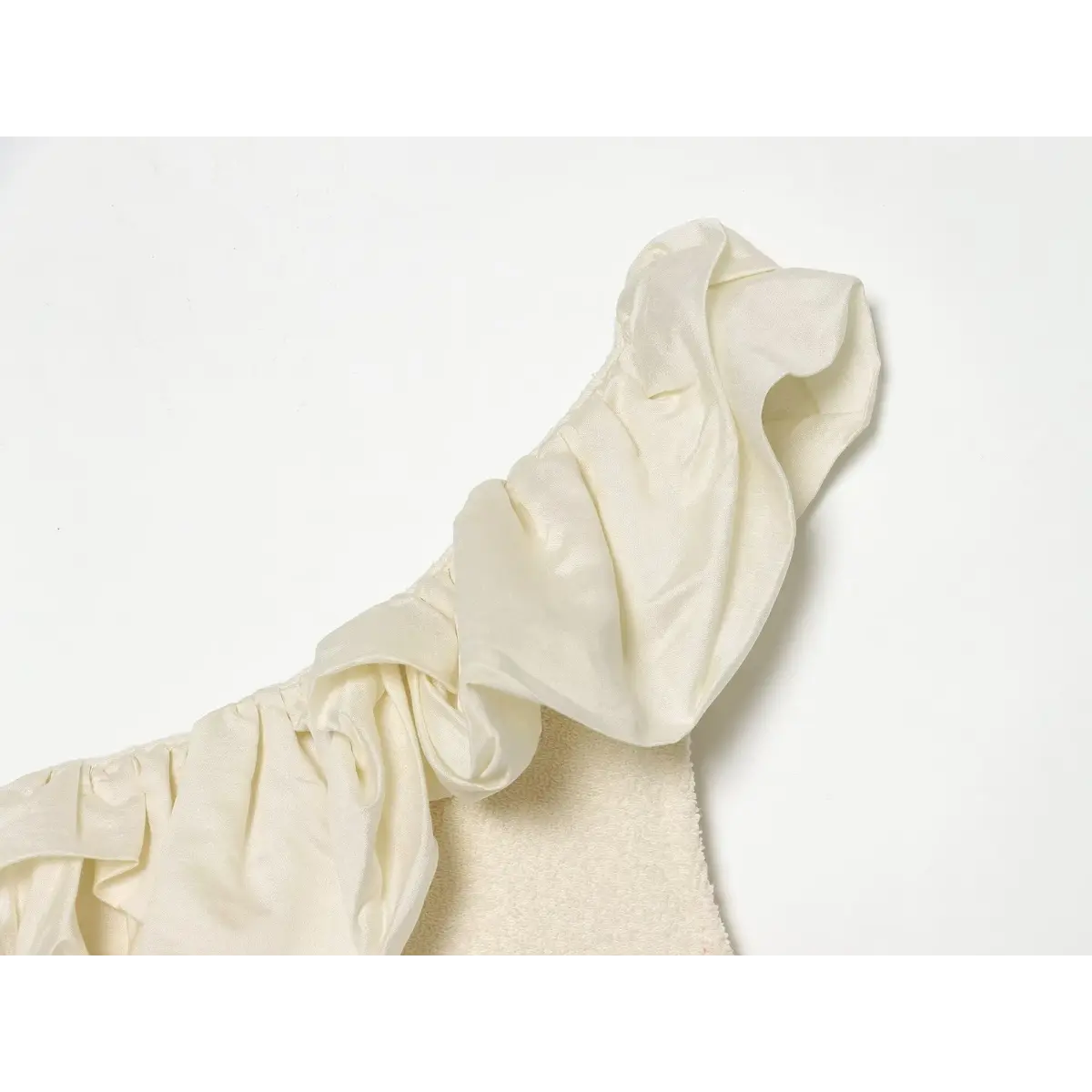 Close of shiny satin big ruffle trim on cream off shoulder knit top neckline