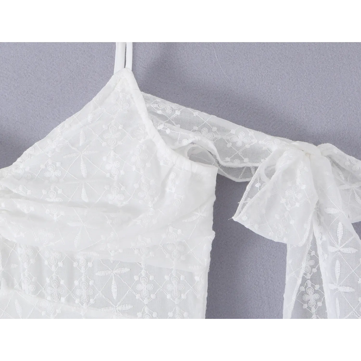Off shoulder sheer fabric tie bow sleeve seam macro close-up, matching eyelet embroidery long ribbon hand tied shoulder binding stitching craft shot