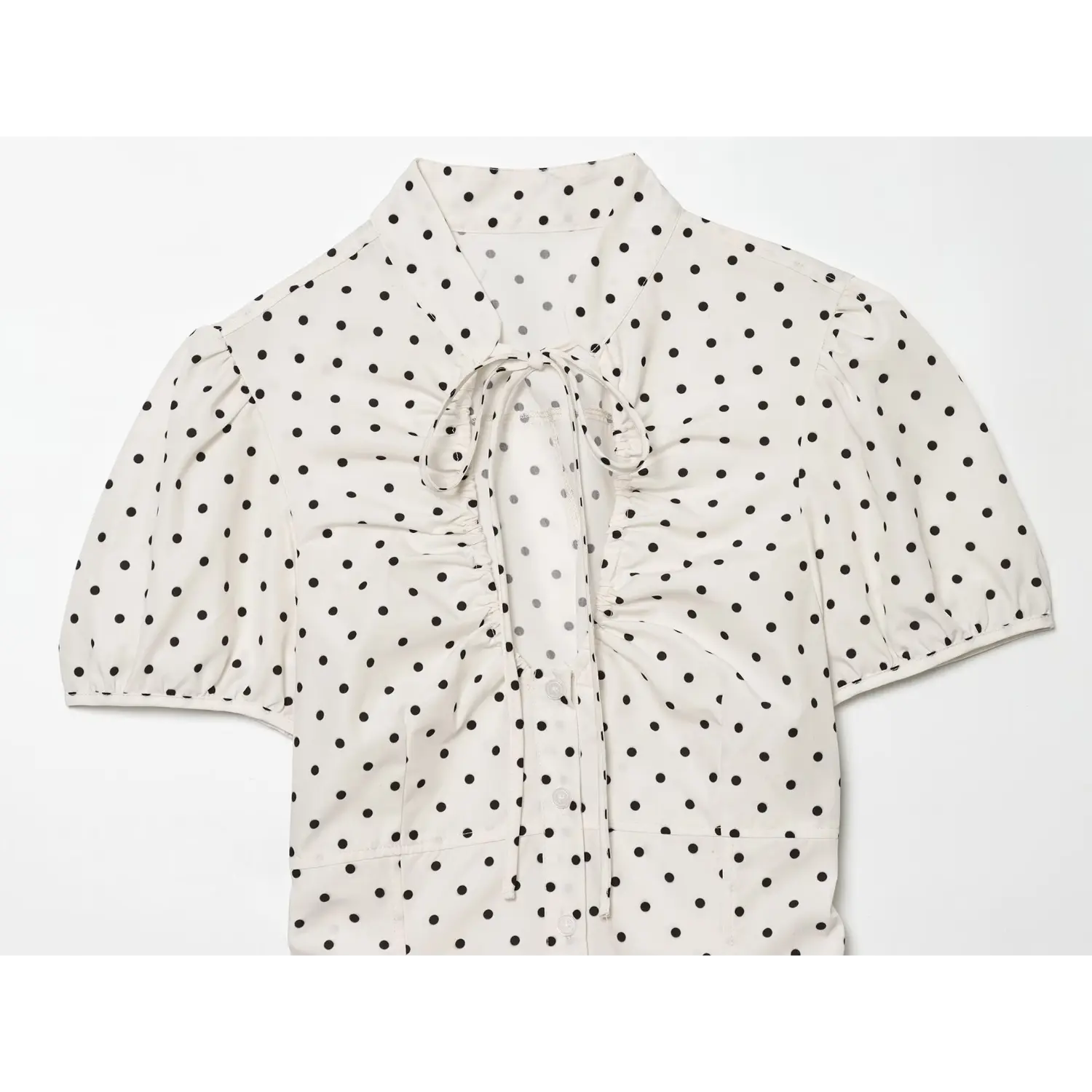 Front flat product shot off white black polka dot blouse, tie v neck, bust ruched detail, puff short bubble sleeve, front button placket, slim fit
