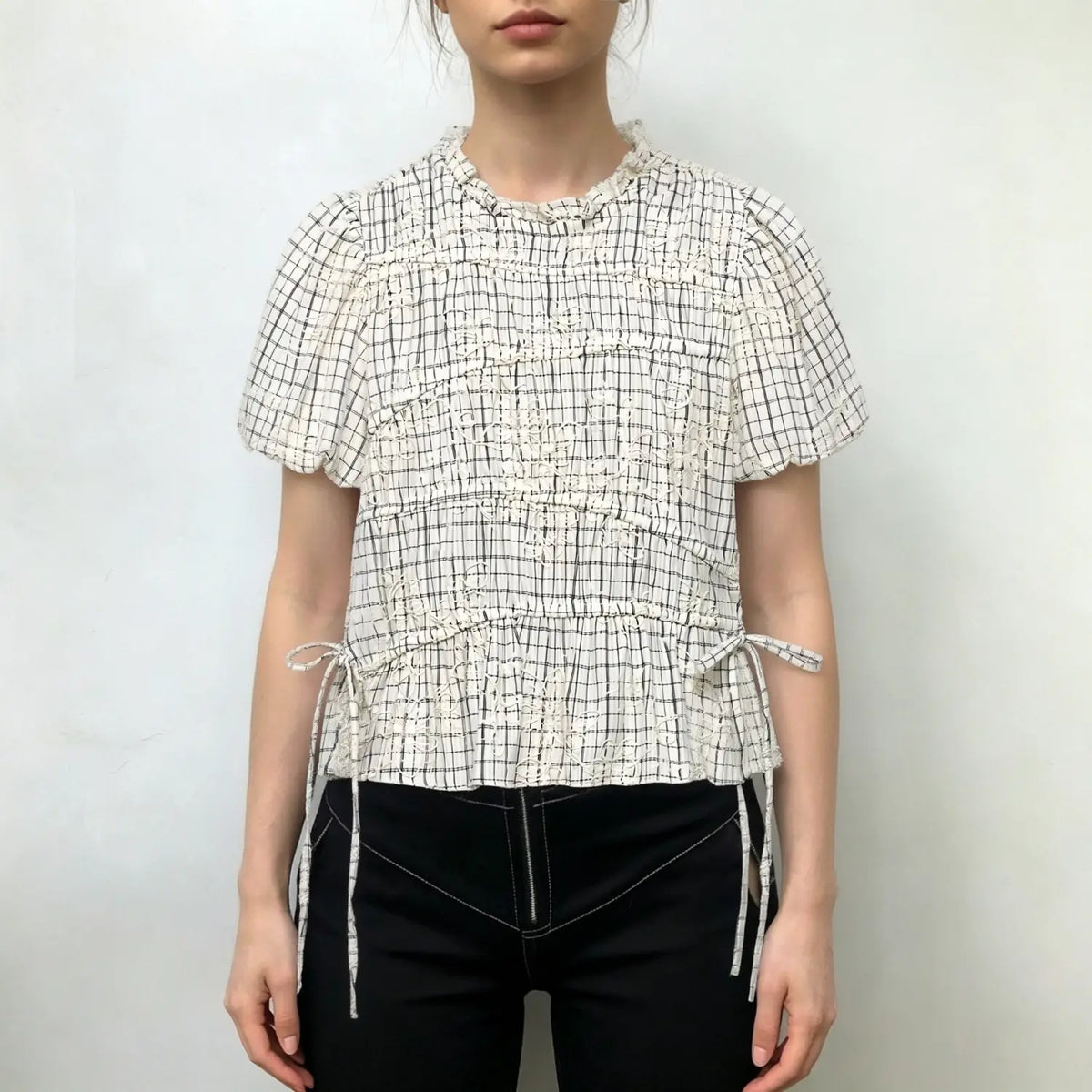 Model wearing off‑white grid embroidered smocked peplum short sleeve blouse