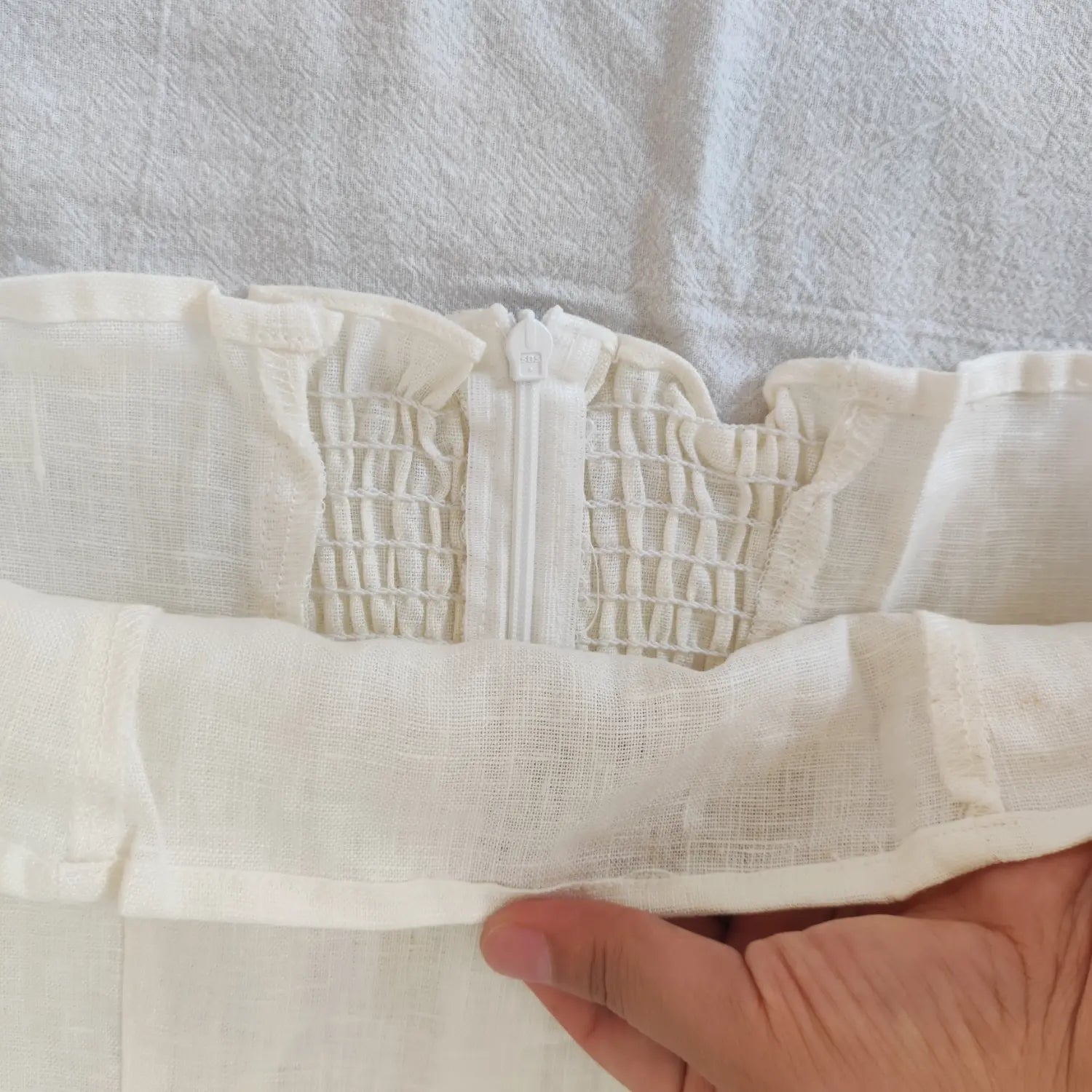 Close‑up center back zipper and inner lining stitching off white linen cami top
