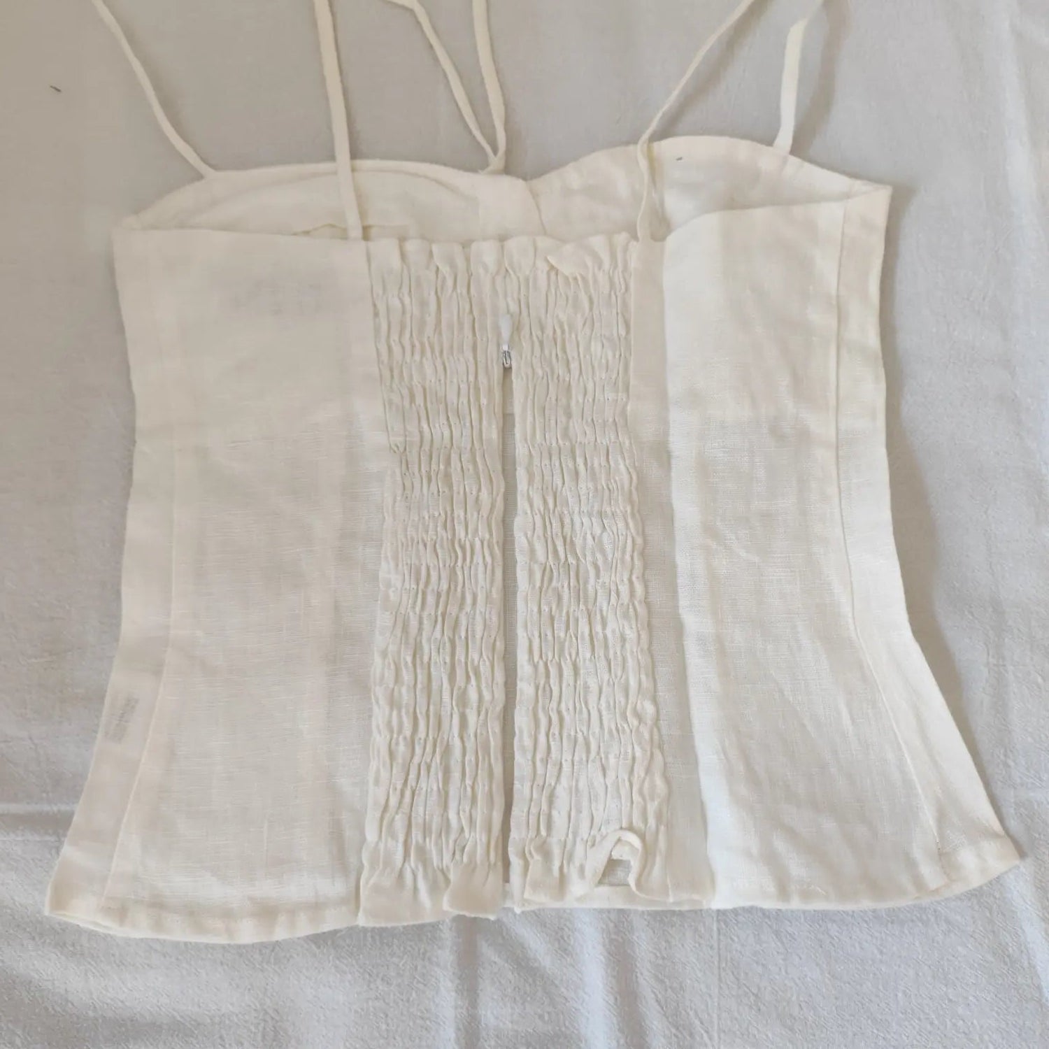 Flat lay back view show full smocked panel and center back zipper off white cami top