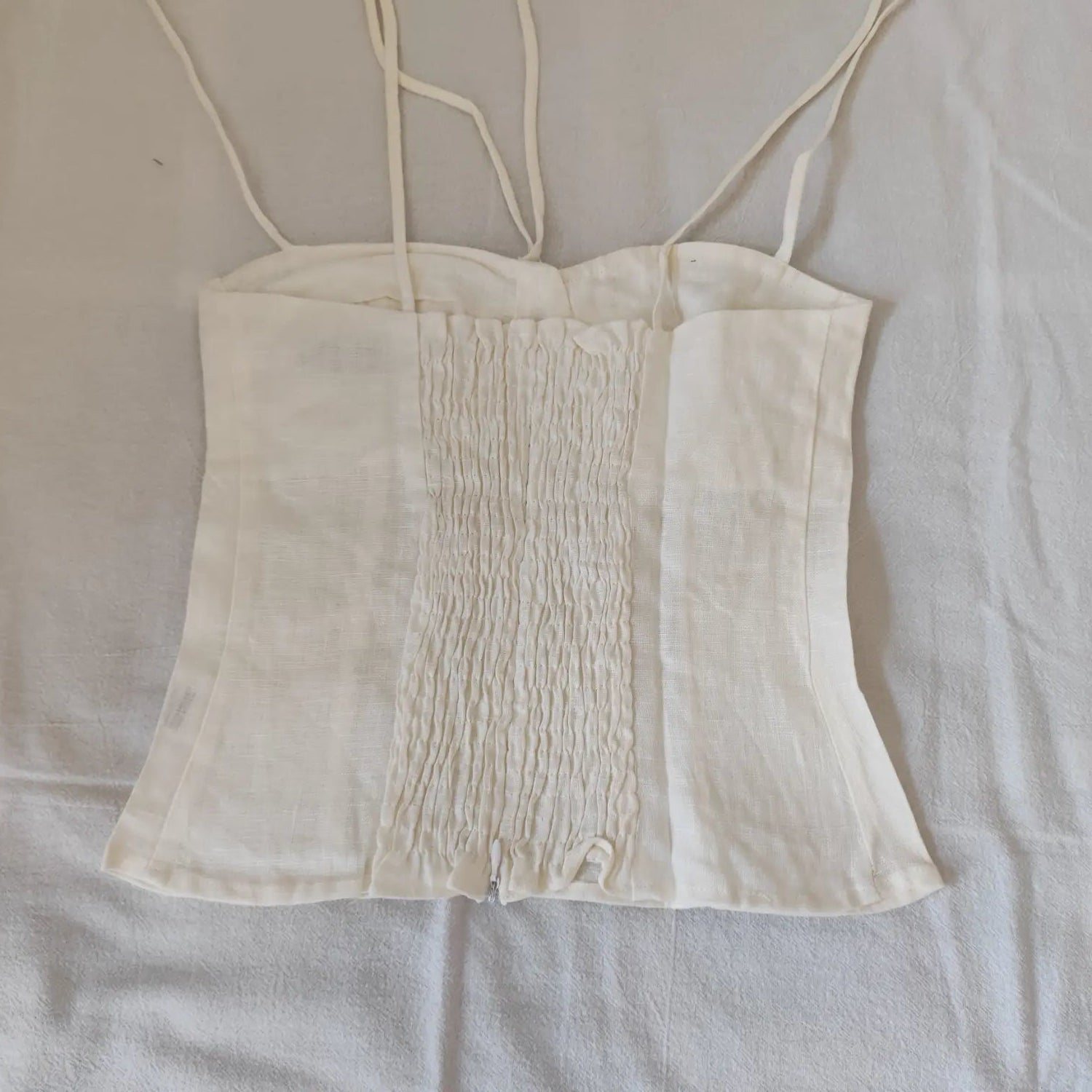Flat lay back view off white linen cami top with smocked panel and back zipper