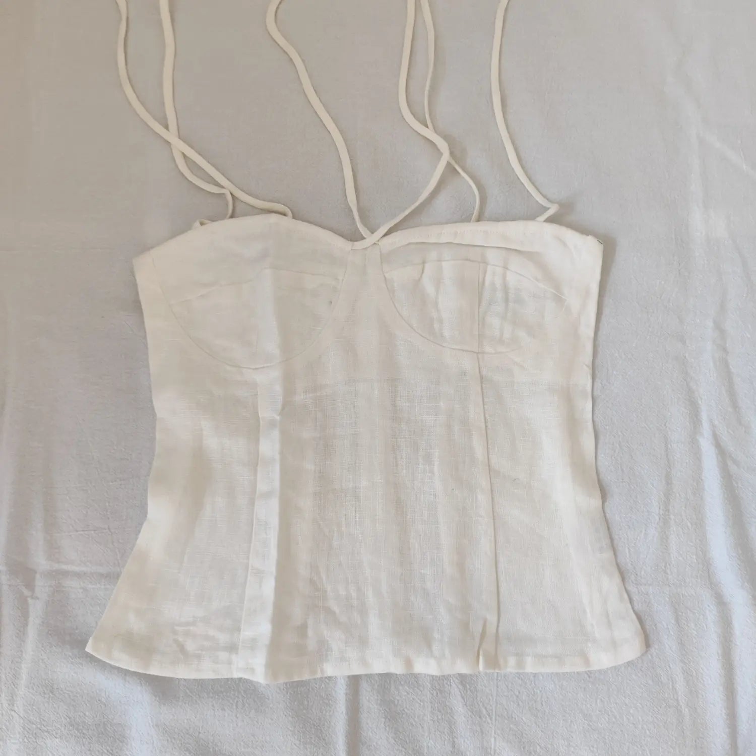 Flat lay front view off white linen cami top with bust dart stitching and tie spaghetti straps