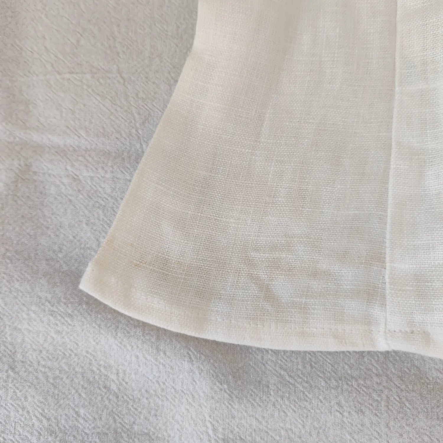 Close‑up bottom hem and linen woven fabric texture of off white camisole top