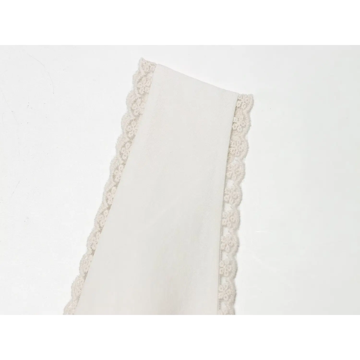Close‑up shot of scalloped floral lace trim on off‑white mini dress strap edge