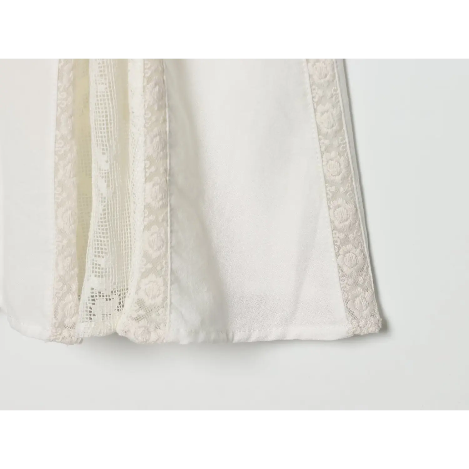 Close‑up of skirt hem floral lace insert panel on off‑white vintage mini dress