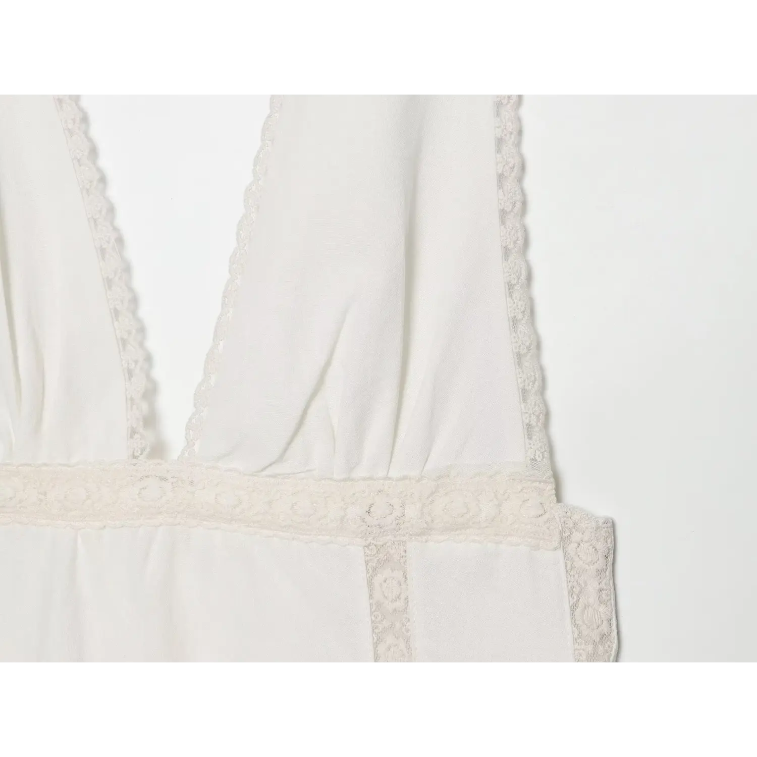 Close‑up of waistband and lace panel detail on off‑white v‑neck mini dress