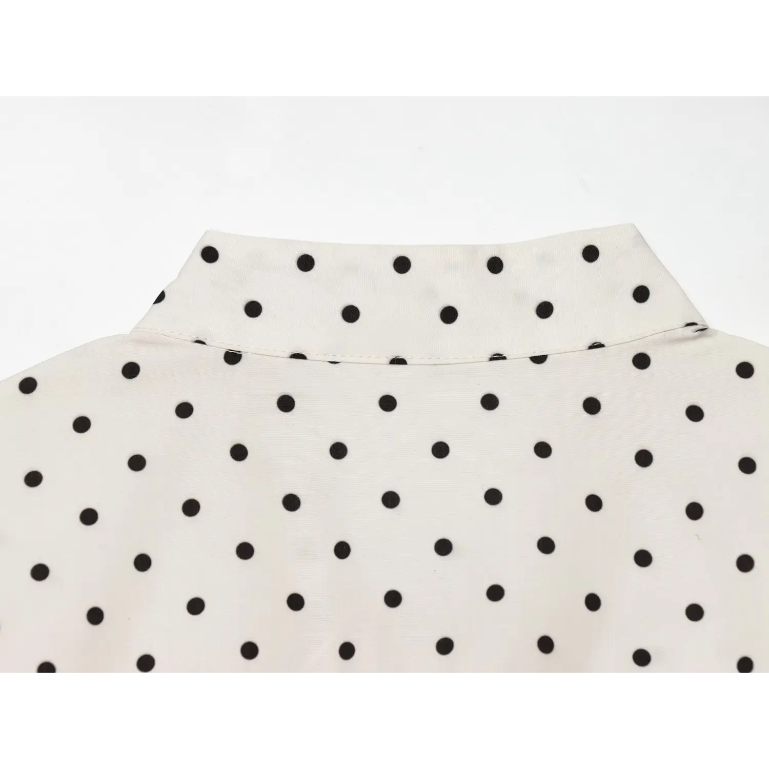 Rear closeup mandarin stand collar, neat back neck stitching, off white black polka dot woven fabric