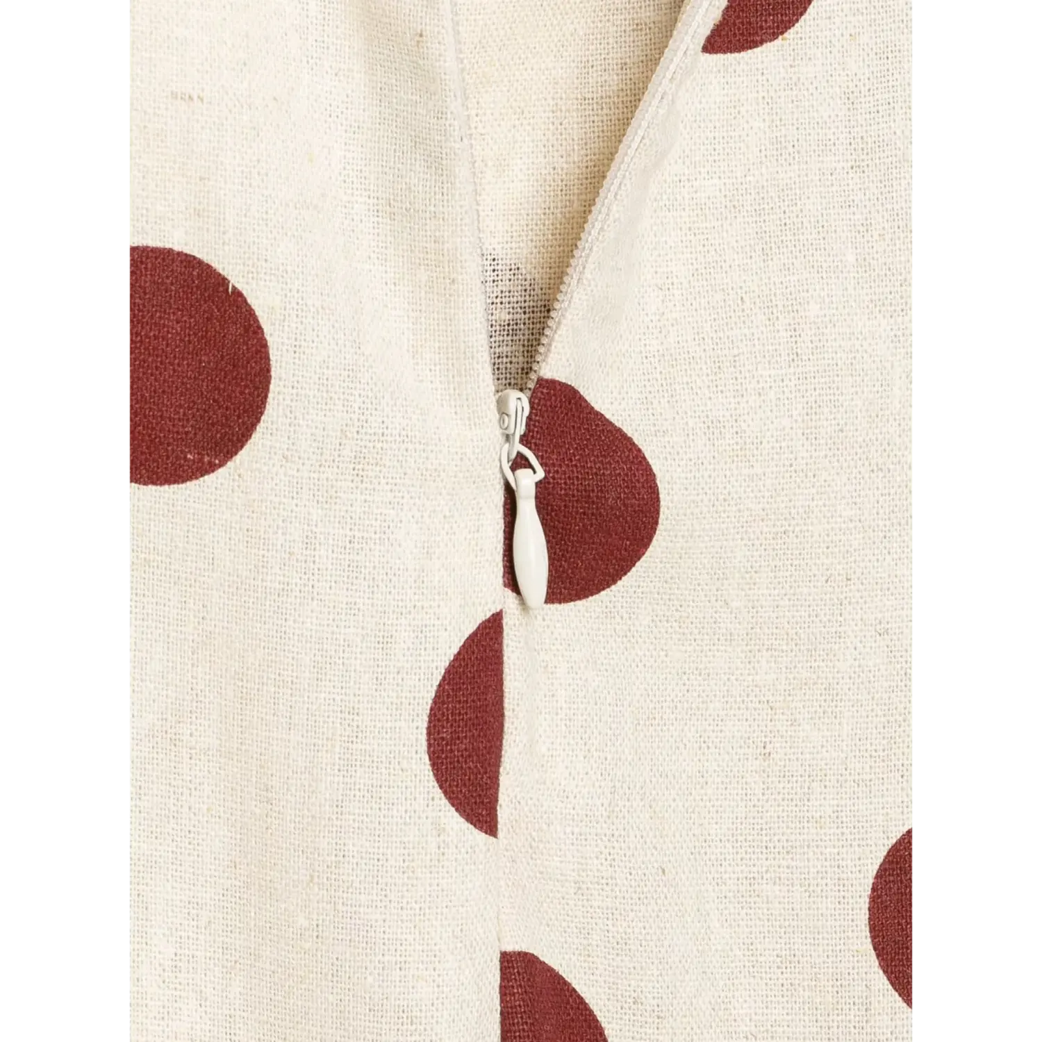 Close-up macro shot of white invisible zipper pull on off-white wine polka dot linen dress