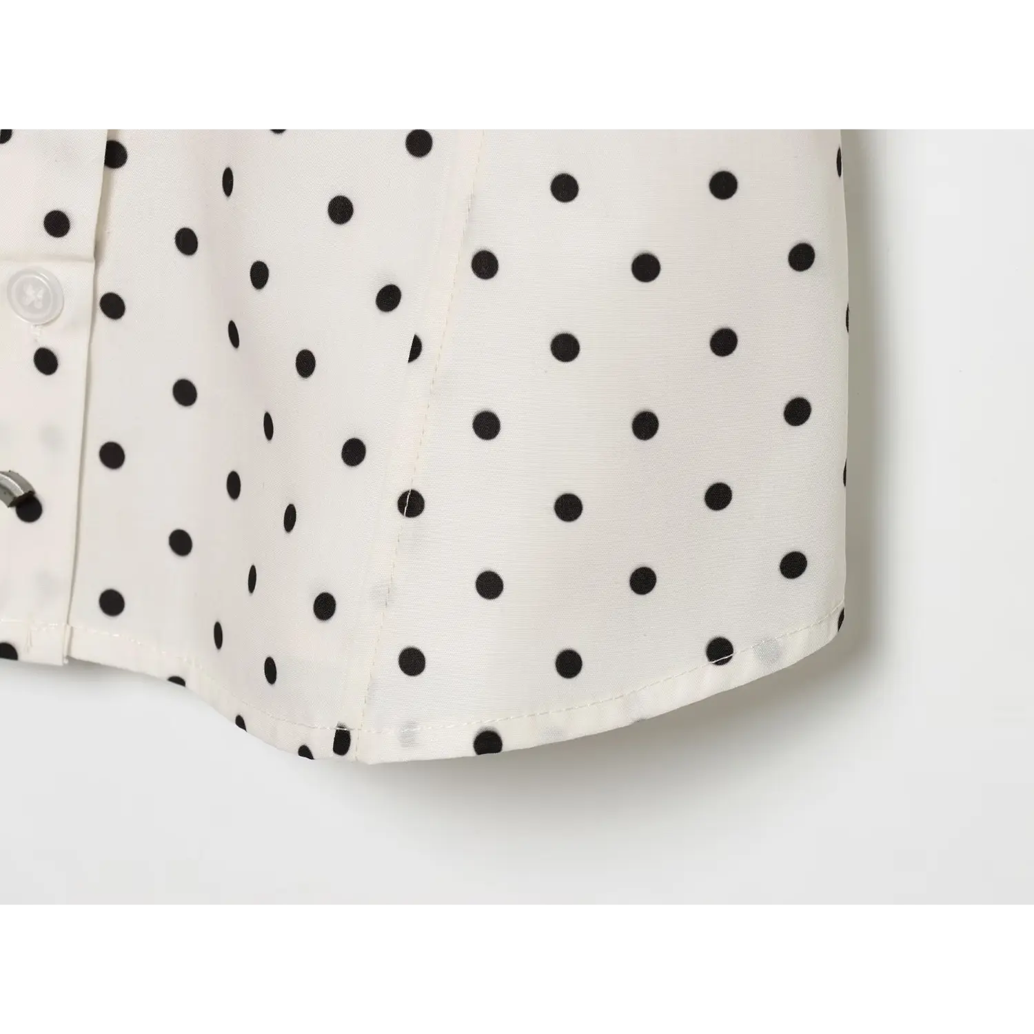 Closeup curved shirt hem, neat finished edge stitching, woven polka dot fabric